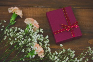 üst görünüm kırmızı hediye kutusu ve kahverengi ahşap tahtalar arka plan üzerinde çiçekler