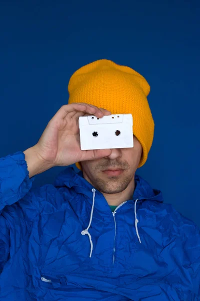 Молодой Человек Ярко Голубой Куртке Жёлтой Шляпе Держит Винтажные Аудиокассеты — стоковое фото