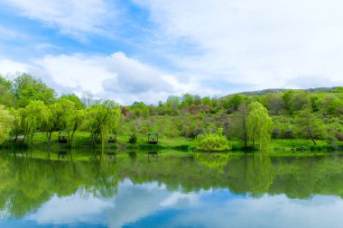 Tahta çardaklar ve göl kıyısında söğütler açık güneşli bir günde ve göldeki yansımaları