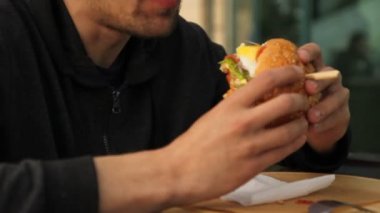 hamburger yiyen genç adam yakın, fast food ve sağlıksız yaşam tarzı kavramı, yumuşak seçici odak