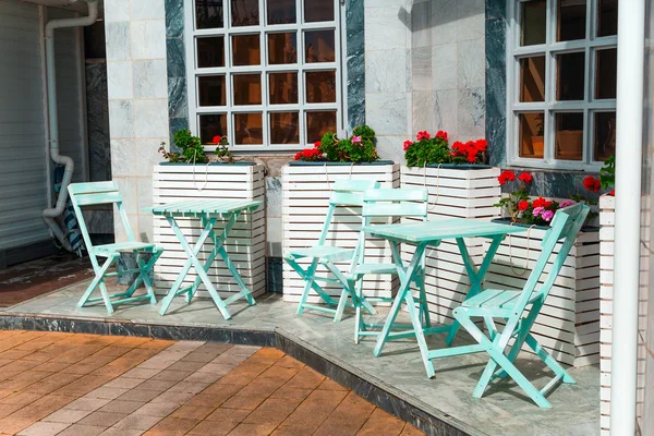 beautiful vintage blue furniture and blooming potted red flowers  on the restaurant terrace on a sunny day
