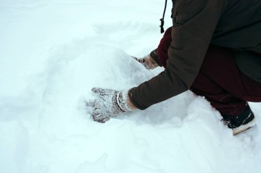 örme eldiven genç adam karla kaplı bir parkta bir kardan adam heykel