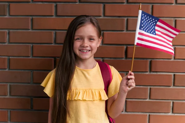 Roztomilá Holčička Usmívá Drží Americkou Vlajku Stojící Před Cihlovou Stěnou — Stock fotografie