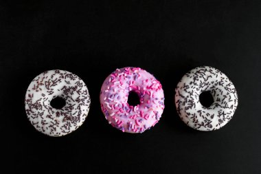 siyah arka planda üst görünüm beyaz ve pembe donut