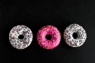 siyah arka planda üst görünüm beyaz ve pembe donut