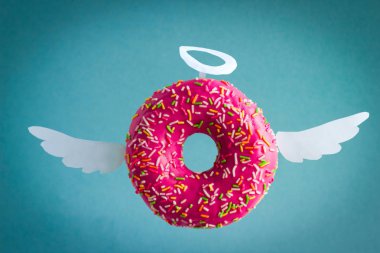 mavi arka planda beyaz kağıt kanatları ve Nimbus ile tatlı pembe çörek