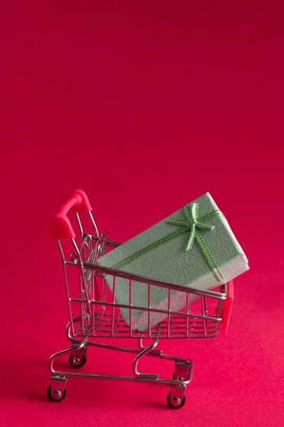 present box in a shopping cart on a pink background