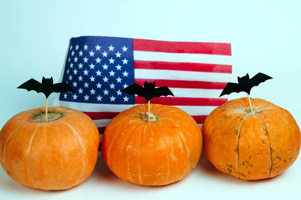 pumpkins decorated with paper cut bats on a  background of american flag