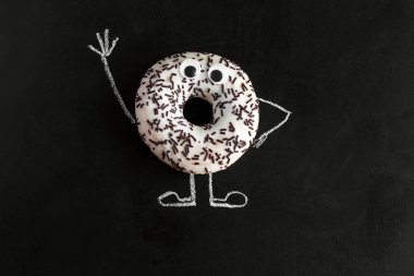 tebeşir çizilmiş kollar ve bacaklar ve googly gözleri ile tebeşir tahtası üzerinde üst görünüm donut