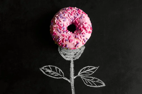top view donut on chalk board with chalk drawn stem and leaves