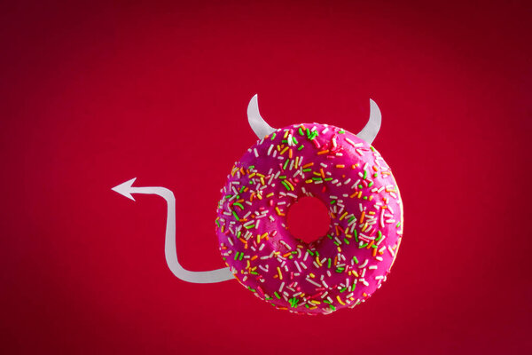 Дьявол пончик с бумажными рогами и хвост летит на красном фоне
