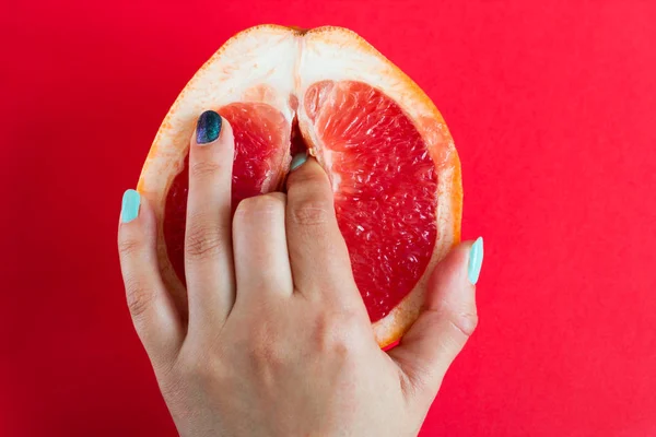 kırmızı arka plan üst görünümünde izole bir greyfurt iki parmak