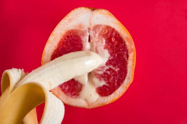 top view half grapefruit, banana and condensed milk on red background clipart