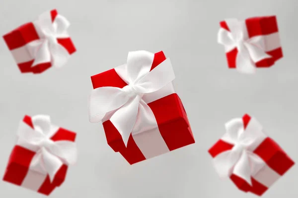 festive red gift boxes with white bows levitating isolated on a gray background