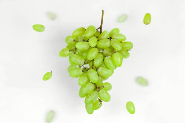 Taze taze organik yeşil üzümler beyaz arka planda havada süzülür, sağlıklı beslenme ve yaşam tarzı