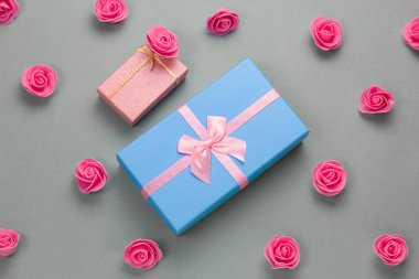 Üst manzara düz hediye kutuları ve gri arka planda pembe gül desenleri vardı.