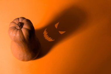 Turuncu arka planda gölgesi olan balkabağı Cadılar Bayramı kartı.