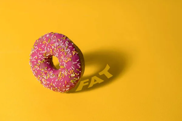 黄色背景的粉红甜甜圈 有脂肪 不健康的营养和生活方式概念的阴影 — 图库照片