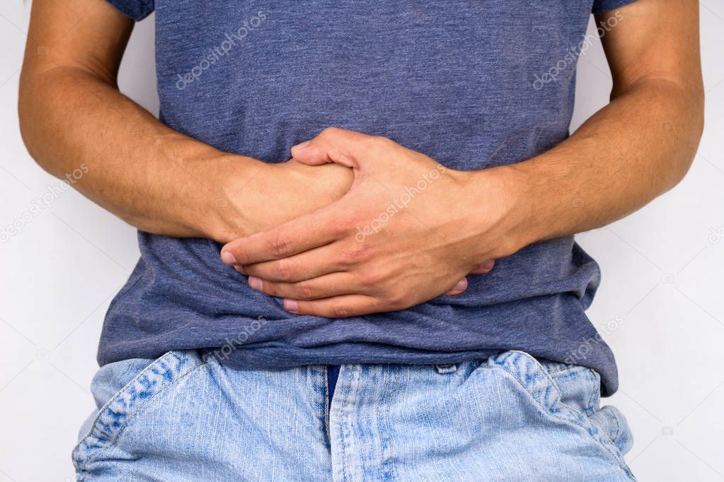young man in jeans and t-shirt holds hands to his stomach, illness concept