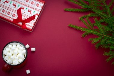 her zaman yeşil ağaç dalları, hediye kutusu ve fincanı kırmızı bir zemin üzerinde marshmallow ile metin için boş alan