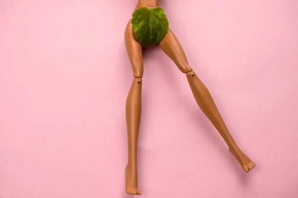 Plastik Bir Bebeğin Bacakları Yeşil Bir Yaprak Ile Pastel Pembe — Stok fotoğraf