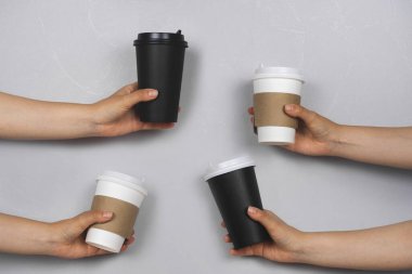 Gri beton bir arka planda servis edilmiş içecek bardakları olan eller.