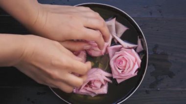 Üst düzey kadın elleri cilt bakımı banyosu, pembe güller ve cilt ve tırnaklar için gül yağı kullanıyor.