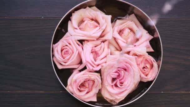 顶部视图水倒在一个碗里 碗上有柔和的粉红色玫瑰 木制背景 温泉和自我护理的概念 — 图库视频影像