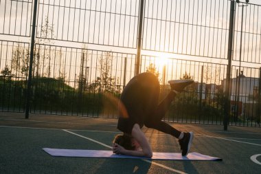 Genç bir atletik kadın basketbol sahasında amuda kalkıyor.