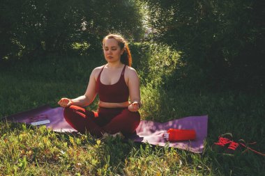 Kırmızı taytlı güzel bir kadın ve şehir parkında yoga yapan bir kadın.