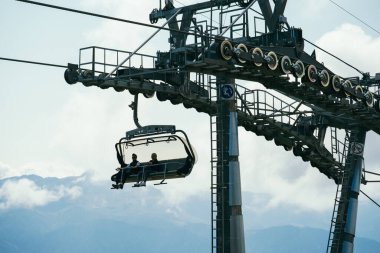 Sochi, Rusya, 17 Eylül 2020. Sabahları mavi sisli yüksek dağların bulanık arka planında teleferikle hareket eden bir turist.
