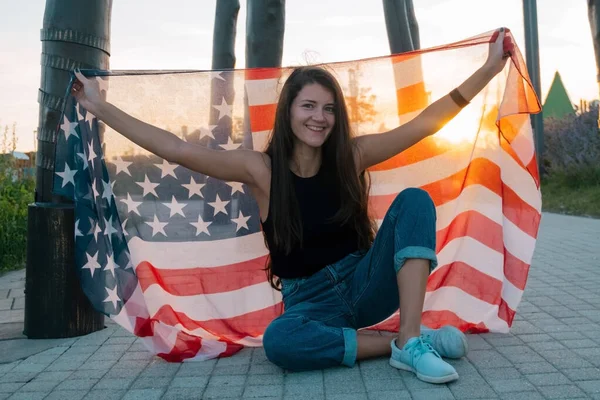 Красивая Молодая Женщина Сидит Скейтборде Держит Флаг Сша Парке Закате — стоковое фото
