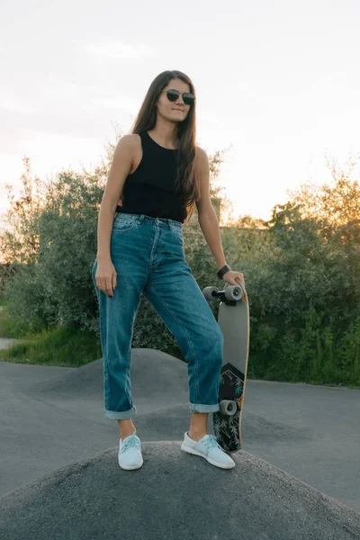 portrait of young woman with skateboard at the sunset