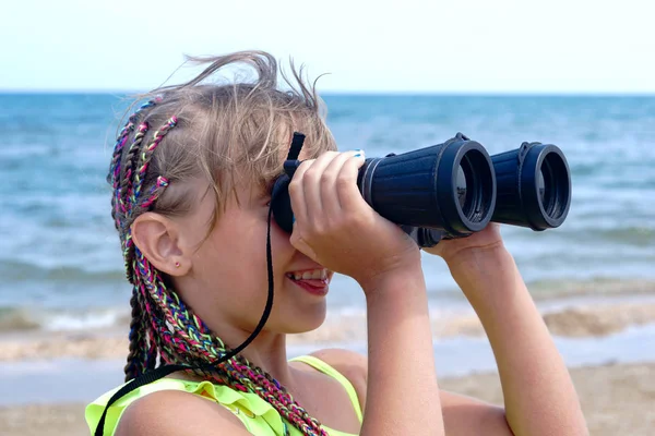 海滩上的小女孩看着望远镜在海面上 图库图片