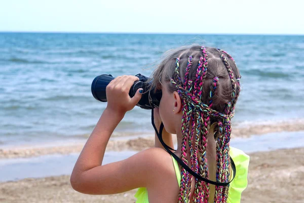 海滩上的小女孩看着望远镜在海面上 免版税图库图片