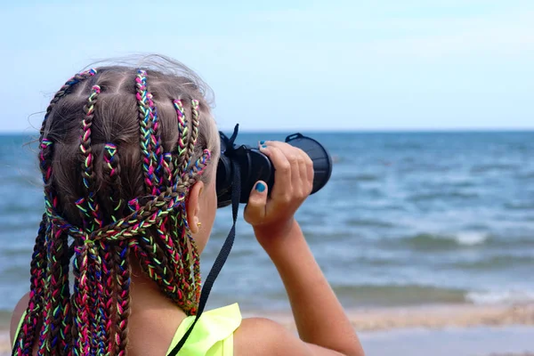 海滩上的小女孩看着望远镜在海面上 免版税图库照片