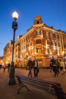 Moskova, Rusya - 21 Eylül 2017: İnsanlar ve mavi gökyüzü ile alacakaranlık boyunca street yürüyüş Arbat sıcak ışık tarafından dekore edilmiş tarihi bina.