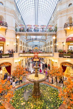 Moscow, Russia - September 16, 2017: Gum department store, the oldest shopping mall decorated by watermelons in fountain roundabout, people walking around. clipart