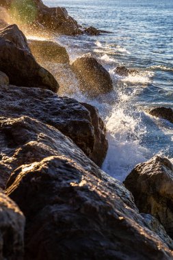 Akdeniz 'in hareketli dalgaları ve suyu kayalara değiyor güneş doğarken havaya biraz su sıçratıyor..