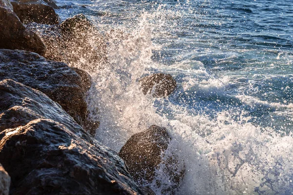 Akdeniz 'in hareketli dalgaları ve suyu kayalara değiyor güneş doğarken havaya biraz su sıçratıyor..