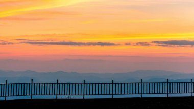 Siluet uzun teras ve çit Dağlar ve alacakaranlık manzaralı.