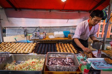 Adam tapınak dışında küçük bir dükkanda takoyaki pişirme