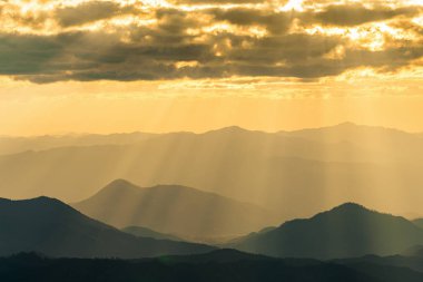 Tayland puslu dağ üzerine bulutlar arasında parlayan Güneş ışığı