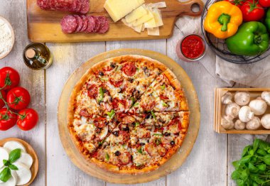 Ahşap tahta ve masa üzerinde taze pişmiş pepperoni pizza, renkli malzemelerle, havai üst görünümü
