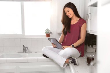 Asyalı Amerikalı öğrenci onu küçük kompakt küçük daire stüdyosu, mutfak onu bilgisayar tablet okuma