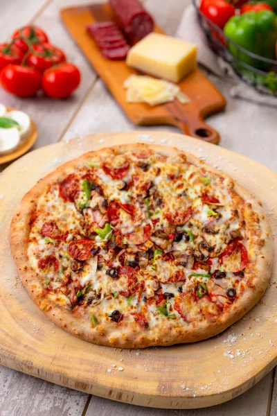 イタリアの食材を使用した木製ボード上のおいしい焼きたての野菜と肉ピザ — ストック写真