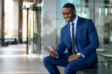 Afro-Amerikan işadamı neşeli gülümseyen, ofis binasında cep telefonu kullanarak, internet, geniş bant, 5g, kopya alanı 