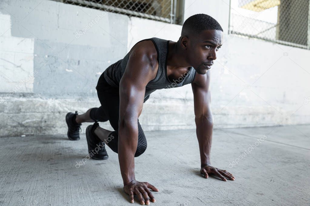 African american male athlete preparing for a jog, stretching, fitness and exercise in urban theme