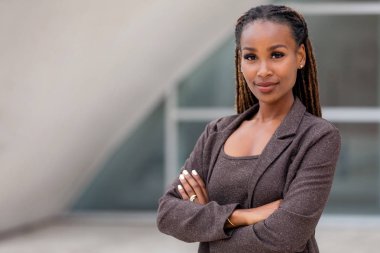 Beautiful female african american business woman CEO in a suit at the workplace, standing confidently with arms folded clipart