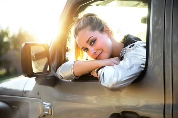 自然の中で車の中で運転美しいブロンドの女性からかわいい楽しい浮気笑顔 車の中で冒険と自由 ストックフォト